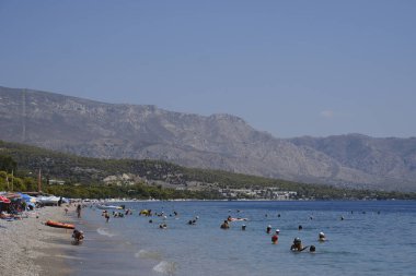 Yunanistan 'ın Moreloponnese kentindeki sıcak bir yaz gününde 23 Ağustos 2024' te Agioi Theodoroi plajında insanlar serinliyor..