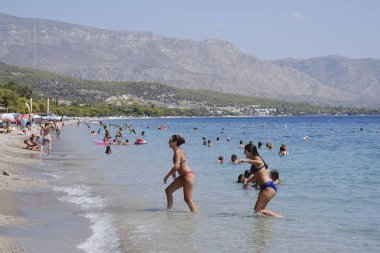 Yunanistan 'ın Moreloponnese kentindeki sıcak bir yaz gününde 23 Ağustos 2024' te Agioi Theodoroi plajında insanlar serinliyor..