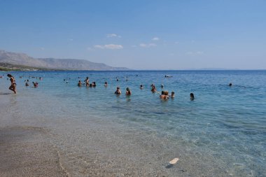 Yunanistan 'ın Moreloponnese kentindeki sıcak bir yaz gününde 23 Ağustos 2024' te Agioi Theodoroi plajında insanlar serinliyor..