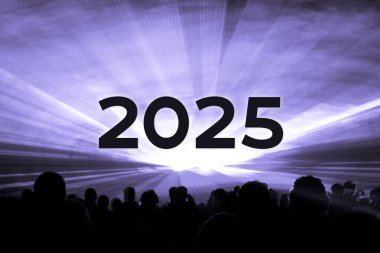 Mutlu yıllar 2025 mor lazer şovu, parti insanları. Yılın dönümünde seyirci siluetleriyle lüks eğlence. Tatil sezonunda özel gece hayatı etkinliği.
