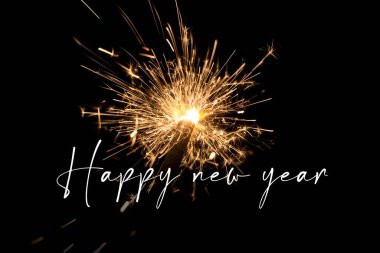 Mutlu yıllar turuncu maytaplı yeni yıl arifesi. Yıl dönümünde yapılan lüks eğlence kutlamaları. Koyu arkaplanda parlayan ışık kıvılcımlarıyla kaliteli gece hayatı görüntüsü.