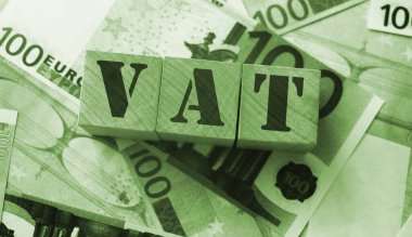 Tahta alfabe küplerine KDV uygulanacak ve etrafta 100 avro banknot olacak. Seçici odaklanma. Vergiler ve ücretler finansal konsept.