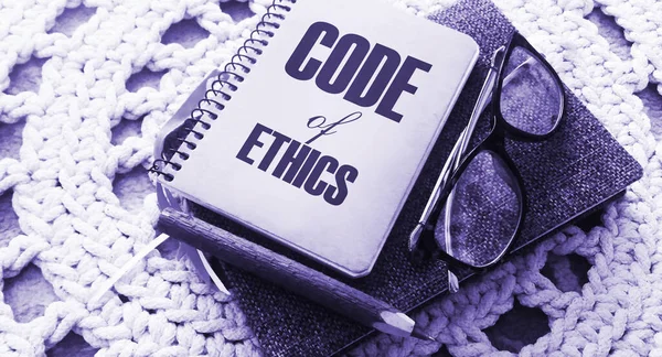 Code Of Ethics words on notebook, pen, glasses, crochet cloth. Business concept. Moral Rules Ethical Integrity Honesty Good procedure.