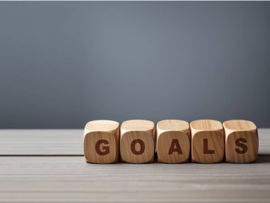 Gri bir masada tahta bloklar üzerinde beyaz arkaplanlı hedefler yazılıyor. iş kavramı.