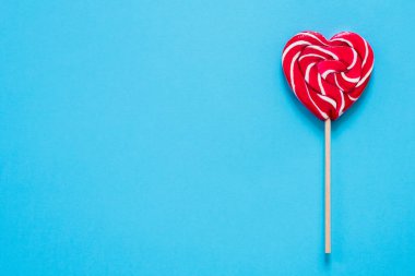 red heart-shaped lollipop on a blue background