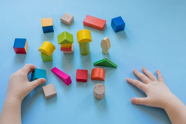 A child builds from colored cubes. Child\'s hands and colored wooden cubes.