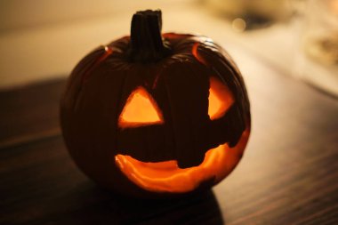 Karanlık arka planda yanan mum olan Cadılar Bayramı kabağı, yakın plan.