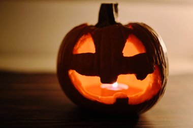 Karanlık arka planda yanan mum olan Cadılar Bayramı kabağı, yakın plan.