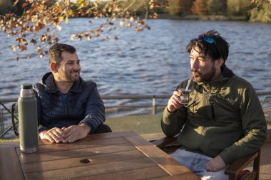 İki arkadaş içki içerken günbatımının tadını çıkarıyor.