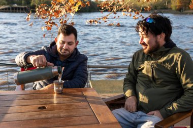 İki arkadaş içki içerken günbatımının tadını çıkarıyor.
