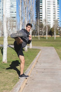 Genç adam parkta Kung Fu çalışıyor.