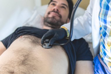 Doktor hastayı muayene etmek için steteskop kullanıyor.