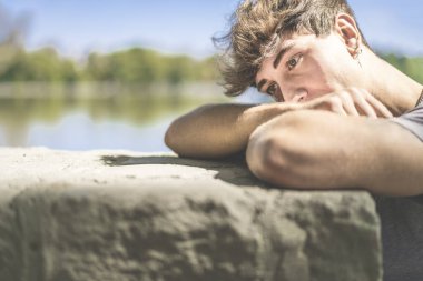 Genç adam, bir vuruşta başını kollarının üzerine düşürür.