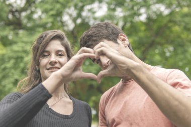 El ele tutuşup kalp yapan bir çift.