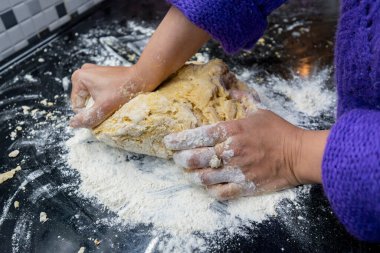Ellerin masada hamur topuzlarını yoğuruyor.