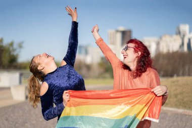 LGBT çifti parkta ellerinde lgbt gökkuşağı bayrağı