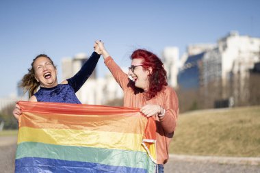 LGBT çifti parkta ellerinde lgbt gökkuşağı bayrağı