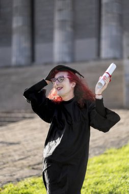 Transseksüel kadın yeni mezun olmuş, kep ve cübbe giymiş, kutlama derecesini gösteriyor..