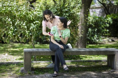 Genç bir adam parkta kız arkadaşına evlilik teklifiyle sürpriz yapıyor. Latin çift.