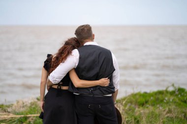 Arkadan bir çifti görmek, kucaklaşmak, sahilde ufka bakmak.