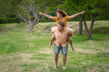 Parktaki mutlu çift. Adam kız arkadaşını sırtında taşıyor.