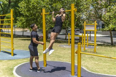 Adamın biri antrenörü onu izlerken barfiks çekiyor.