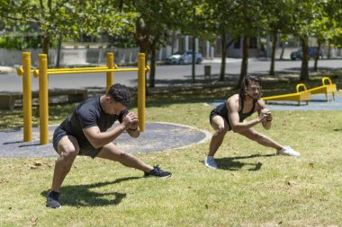 Genç erkekler egzersiz yapmadan önce parkta bacaklarını esnetiyorlar.