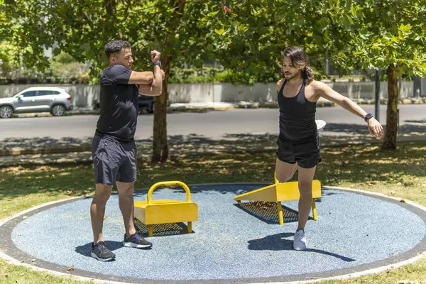 Genç ve zinde Latin erkekler parkta esneklik egzersizleri yapıyor.