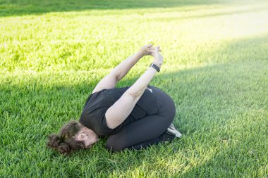 Çimenlerde yoga yapan bir kadın.
