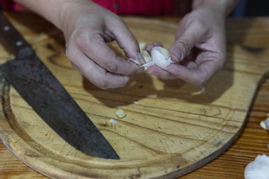 Ev mutfağında dikkatlice sarımsak soyuyorlar.