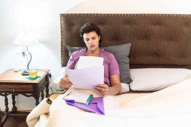 Bir kadın evde rahat bir öğleden sonra geçirirken belge okuyor.