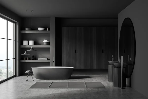 Front view on dark bathroom interior with bathtub, panoramic window with countryside view, large round mirror, double sink, grey walls, concrete floor. Concept of minimalist design. 3d rendering