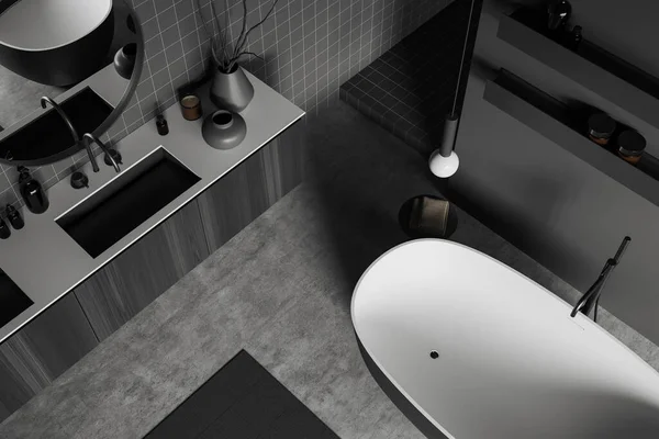 Top view of dark bathroom interior with sink and bathtub. Black wooden dresser and shelf with bathing accessories, grey concrete floor. 3D rendering