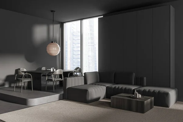Corner view on dark studio room interior with sofa, armchairs, dining table, grey wall, coffee table, carpet, panoramic window with city view, concrete floor. Minimalist design. 3d rendering
