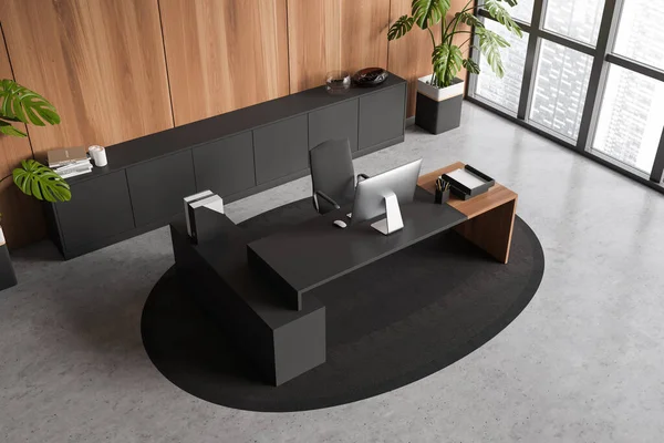 Top view on dark office room interior with desktop, desk, armchair, panoramic window with city view, concrete floor, carpet, sideboard. Concept of company, firm, director workspace. 3d rendering
