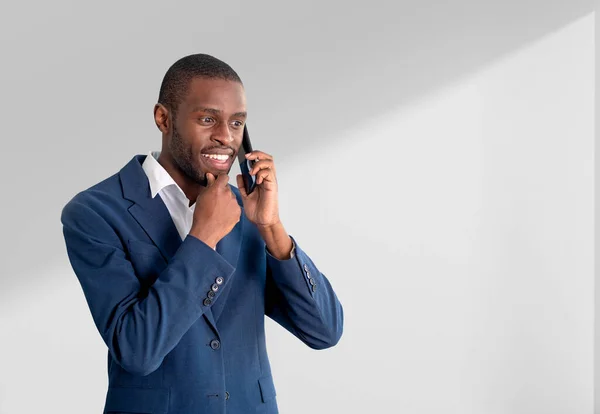 Pensive businessman calling on the phone, hand on chin wearing blue formal suit on empty copy space background. Concept of business network and communication