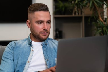Young businessman working with laptop, pensive portrait looking at the screen. Concept of distance work and freelancer