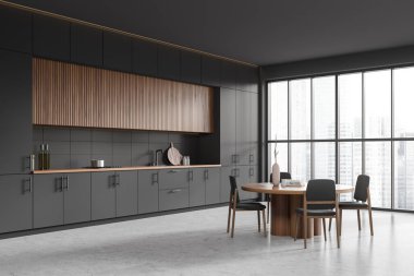 Dark kitchen interior with dining table and chairs, side view grey concrete floor. Cooking corner with shelves and kitchenware, panoramic window on skyscrapers. 3D rendering