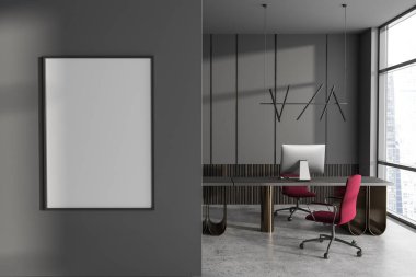 Dark office interior with pc computer on desk, grey concrete floor. Panoramic window on skyscrapers. Mock up canvas poster on partition. 3D rendering