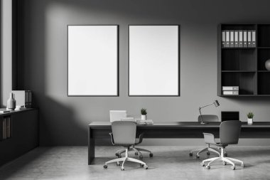 Front view on dark office room interior with two empty white posters, computers, desks, armchairs, shelves, concrete floor. Concept of company, firm, meeting space. 3d rendering