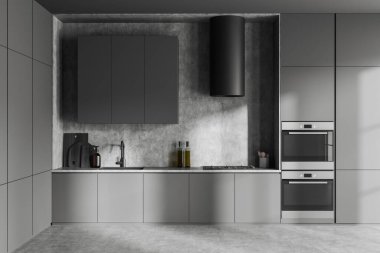 Front view on dark kitchen room interior with cupboard, grey wall, concrete floor, gas cooker, double oven, sink, cooking inventory, desks. Concept of minimalist design. 3d rendering