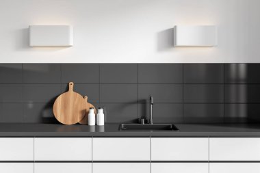 Stylish kitchen interior with sink and deck with minimalist kitchenware. Cooking corner with hidden shelves and lamp on white wall. 3D rendering