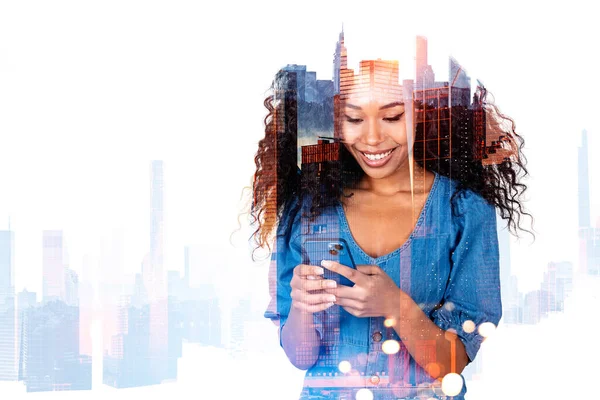 Happy african woman portrait working with phone, double exposure with skyscrapers silhouette. Concept of business network and mobile app