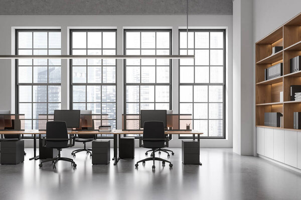 Stylish office interior with coworking zone and shelf with folders, pc computer on desk, grey concrete floor. Panoramic window on Singapore skyscrapers. 3D rendering