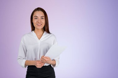 Smiling attractive businesswoman wearing formal wear standing holding pack of documents near empty pale purple wall in background. Concept of ambitious business person, inspired lawyer