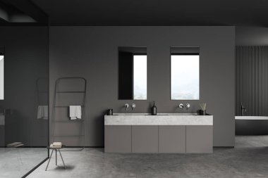 Dark bathroom interior with sink, mirror and bathtub on grey concrete floor, window on countryside. Table with towel and rail ladder, modern hotel studio. 3D rendering
