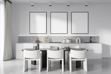 Front view on bright kitchen room interior with three empty posters, dining table with armchairs, cupboard, white wall, concrete floor, gas cooker. Concept of minimalist design. Mock up. 3d rendering