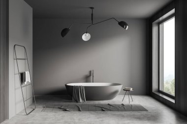 Dark bathroom interior with bathtub, table with accessories, towel rail ladder and grey concrete floor. Washing space in hotel apartment with panoramic window on countryside. 3D rendering