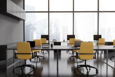 Dark office interior with table, armchairs and laptop. Coworking zone with pc computer in row near panoramic window on Singapore skyscrapers. 3D rendering