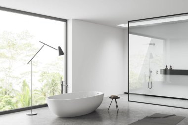 White bathroom interior with bathtub and shower behind glass partition, grey concrete floor. Modern hotel studio with panoramic window on tropics. 3D rendering